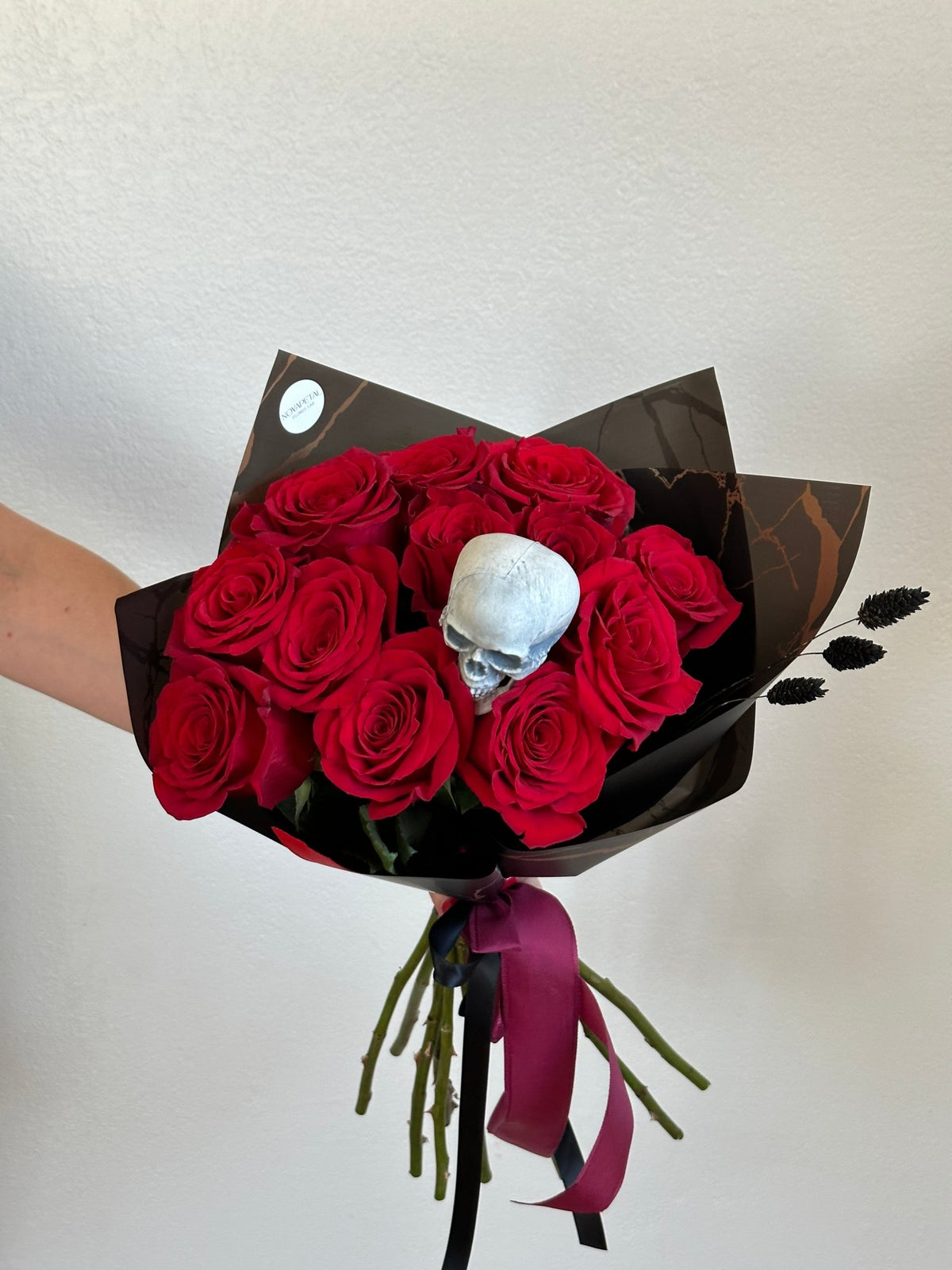 Halloween bouquet of 12 red roses in black and bronze wrap with a white skull, black ribbon and burgundy ribbon