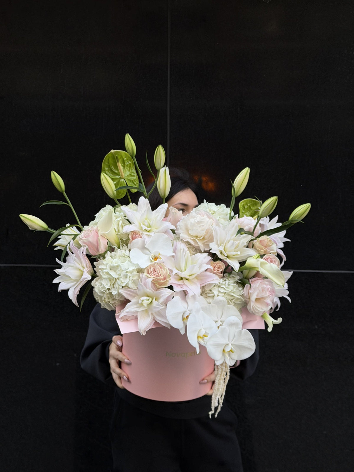 Florist holding the Chloe hat box arrangement of double lilies and white orchids, Large size
