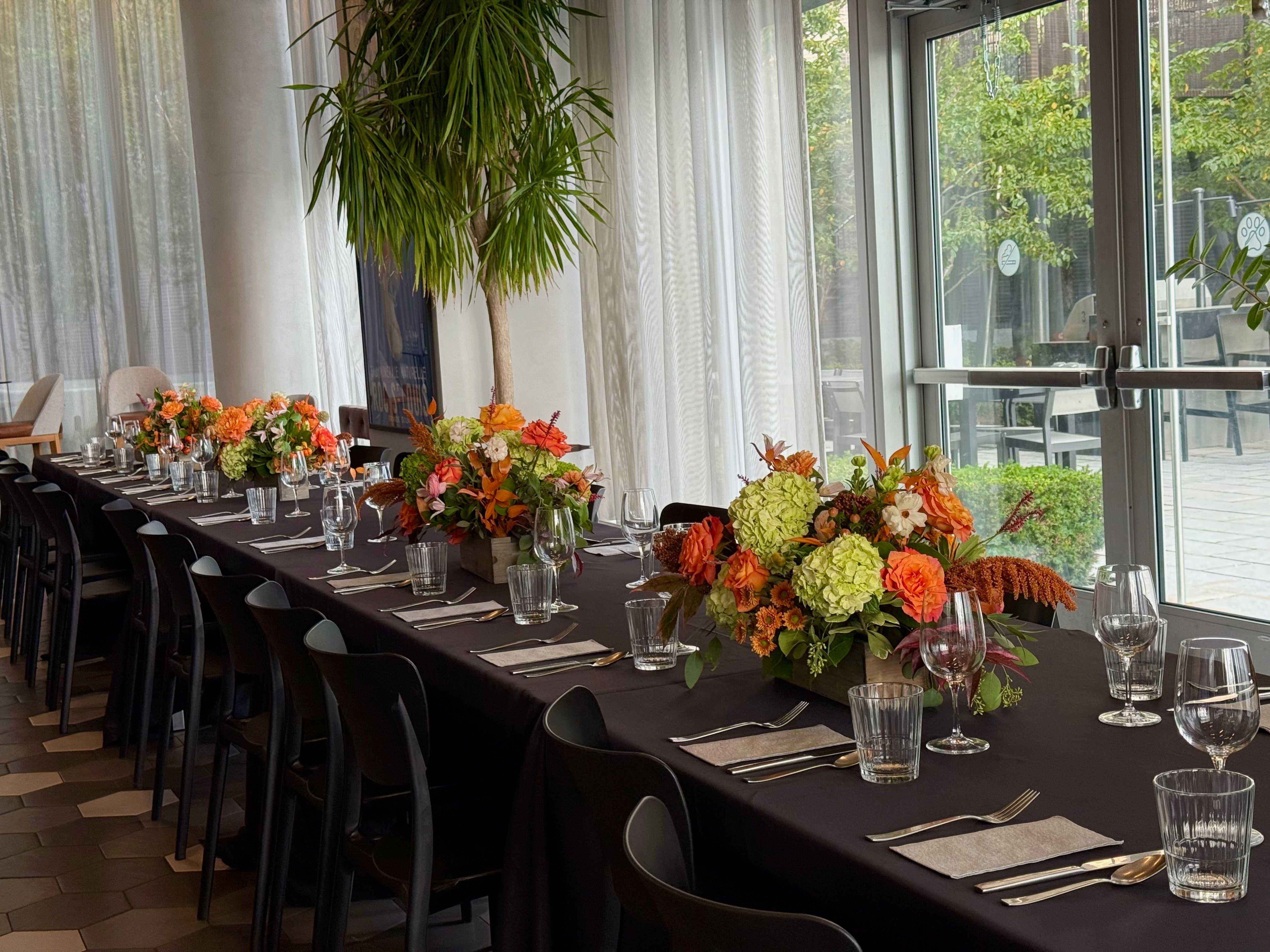 Elegant dining setup with floral arrangements and glassware in a modern interior.