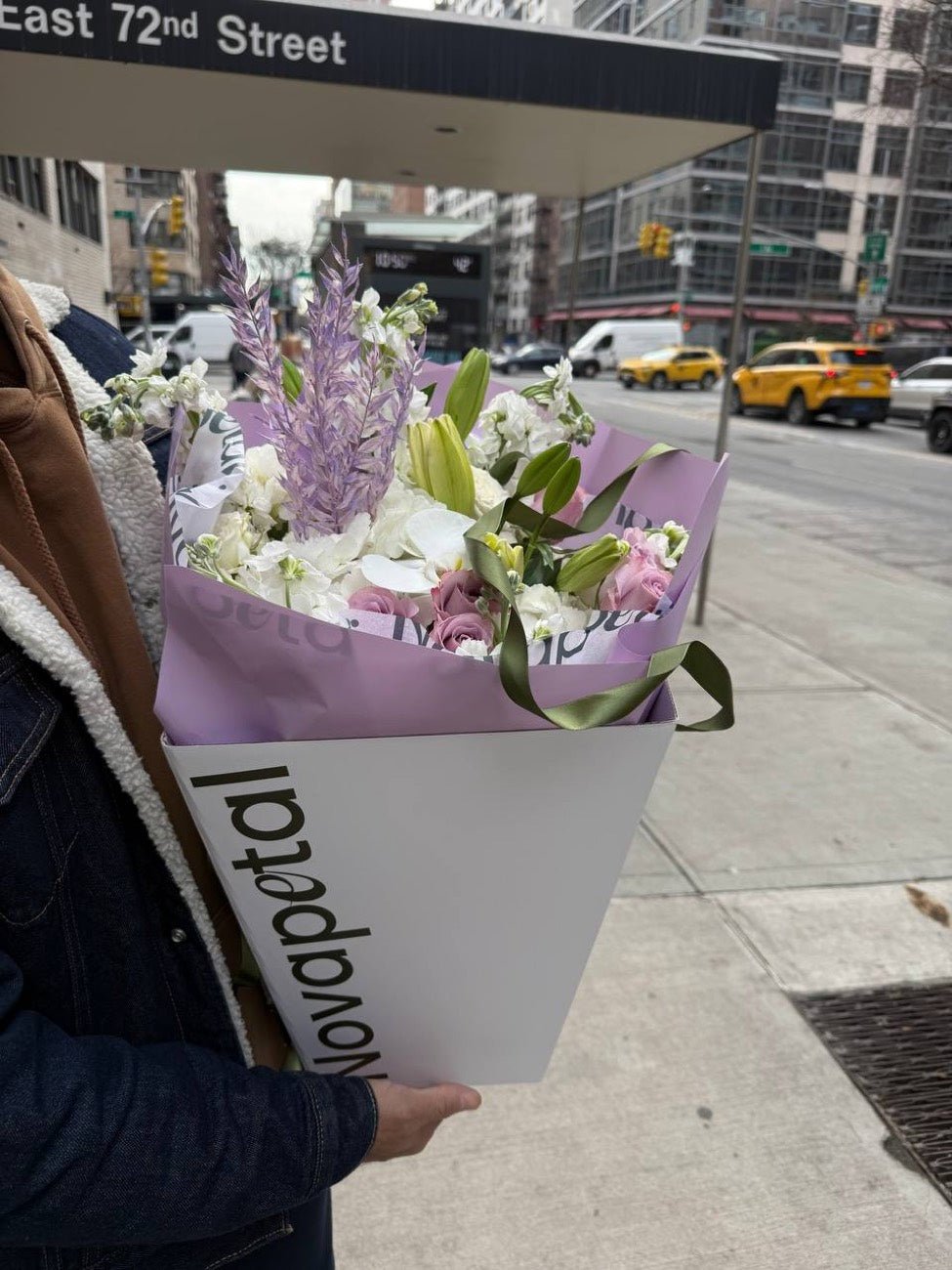 A Novapetal gift bag with a lilac and white bouquet at the East 72nd Street subway entrance in Manhattan