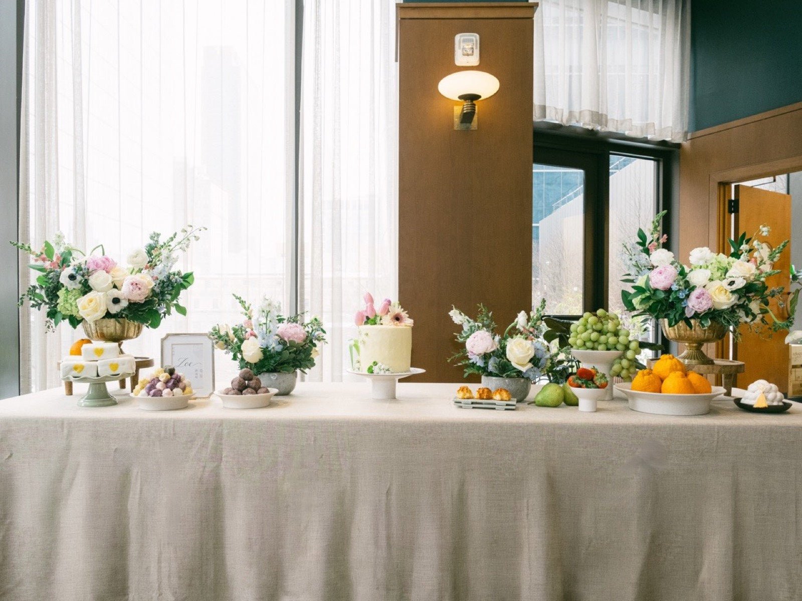 Baby shower dessert table in New York styled with pastel peony, garden rose and anemone arrangements, a floral cake and fruit