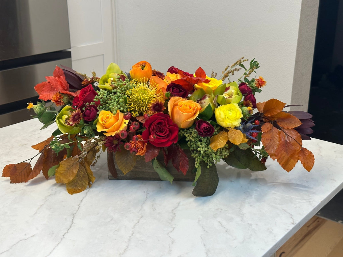 Side view of a low autumn table arrangement in red, orange, yellow and green