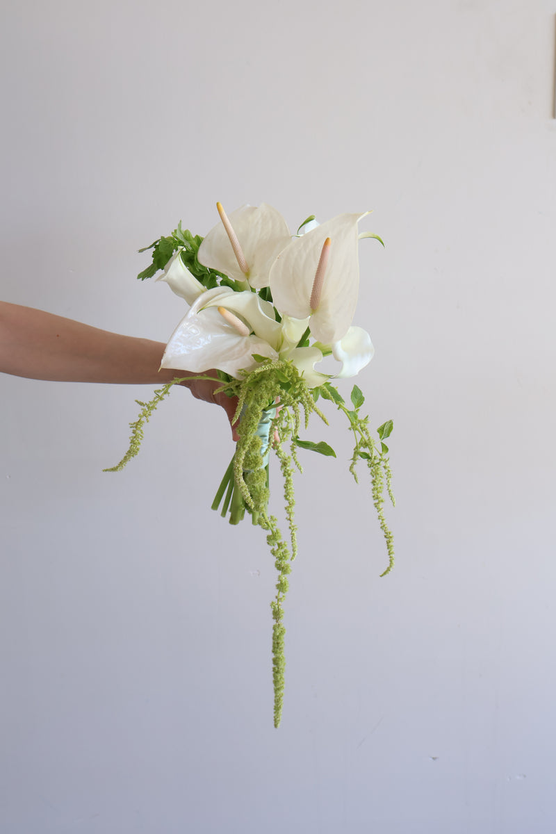 White calla lilies and trailing amaranthus in a hand-tied bridal bouquet