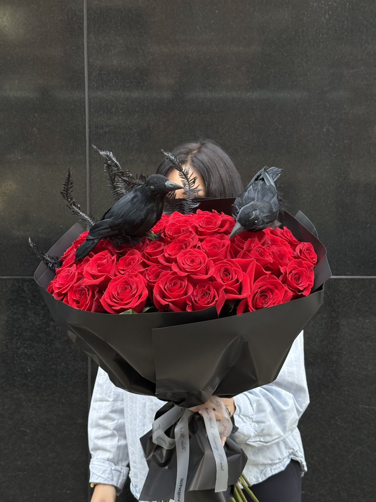 Bouquet of deep red roses with black ferns and two black ravens, wrapped in matte black paper