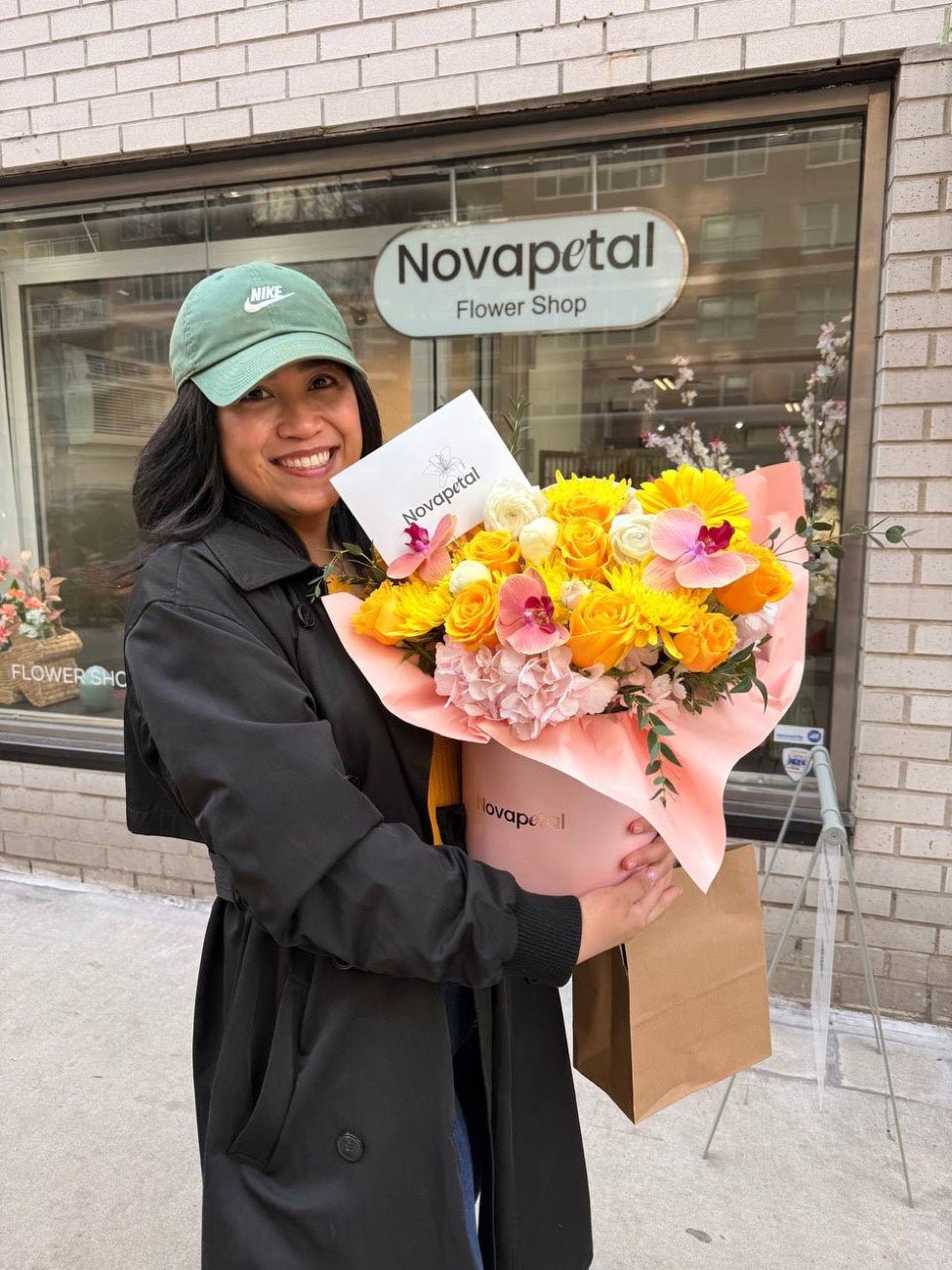 A customer outside Novapetal Flower Shop on the Upper East Side holding a wrapped bouquet of yellow roses and orchids