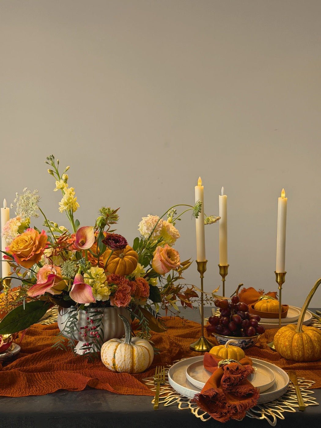 Autumn centerpiece of garden roses and calla lilies with mini pumpkins and taper candles