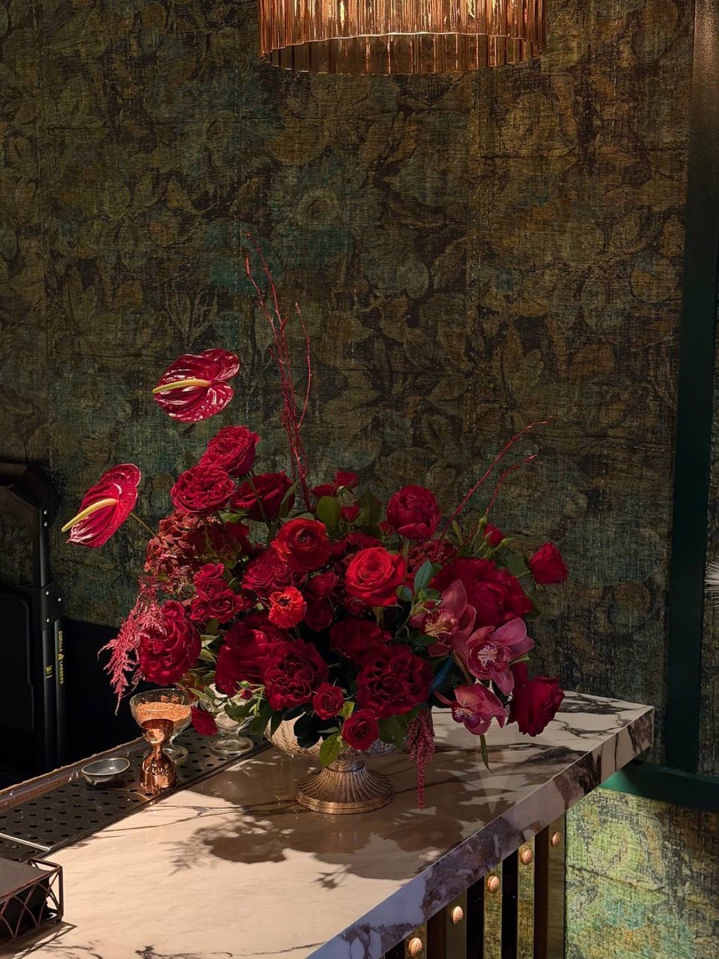 Deep red rose and orchid centerpiece on a marble bar