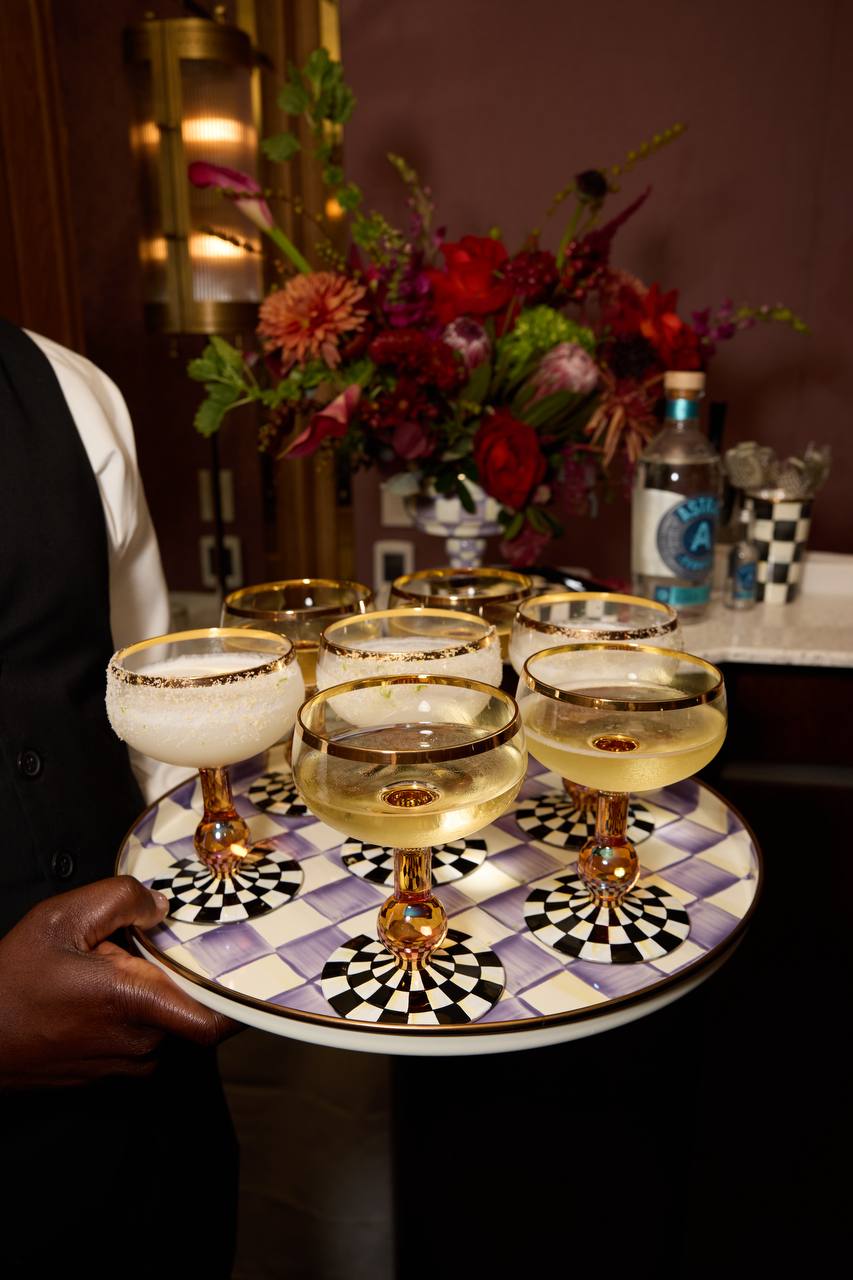 Deep red and plum centerpiece behind a tray of coupe glasses at the MacKenzie-Childs x Practical Magic 2 launch