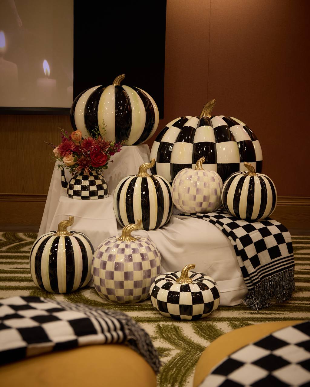 Coral rose and dahlia arrangement in a checked teapot beside MacKenzie-Childs pumpkins at the Practical Magic 2 screening in New York