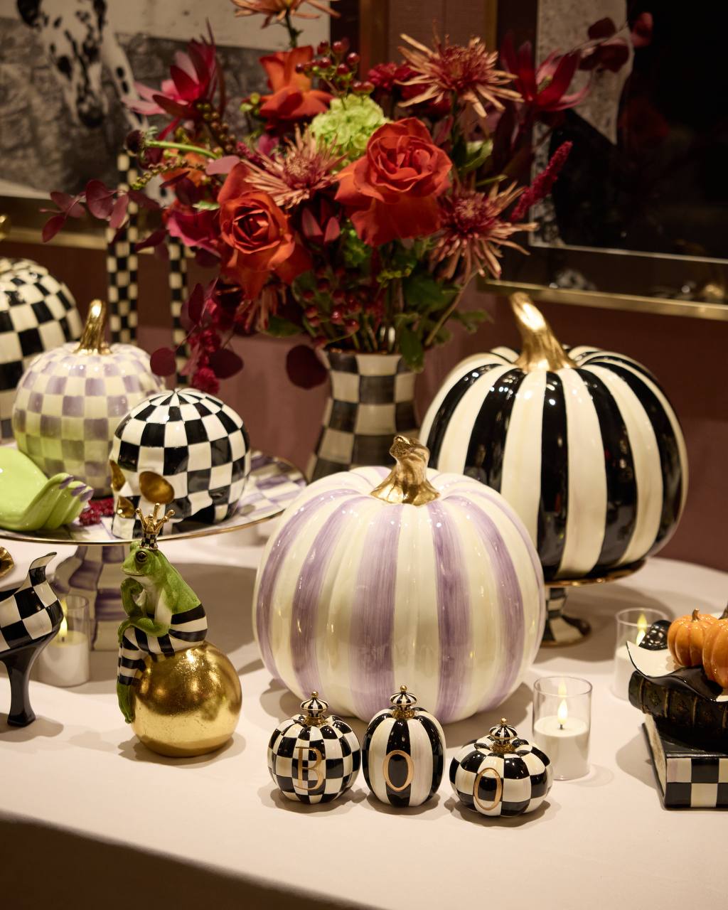 Red and orange rose, chrysanthemum and berry arrangement in a checked vase at the MacKenzie-Childs x Practical Magic 2 launch in New York