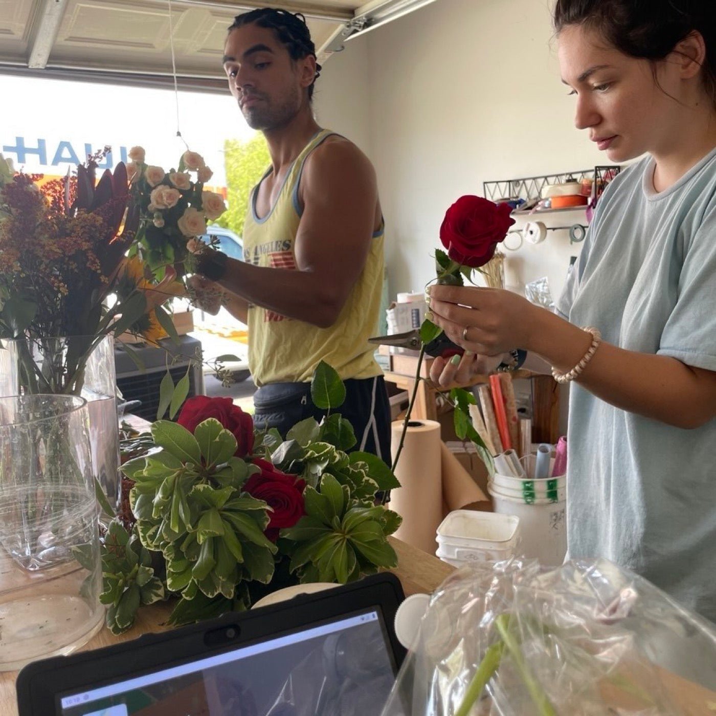 Olga and Anthony Sheppard making flower arrangements in the Phoenix garage where Novapetal started in 2021, the garage door open behind them