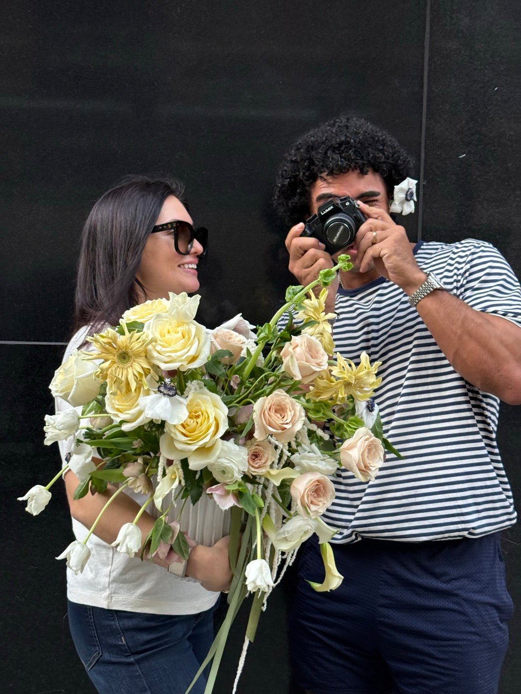 Anthony Sheppard photographing a finished cream and yellow arrangement held by Olga Sheppard before it leaves for delivery
