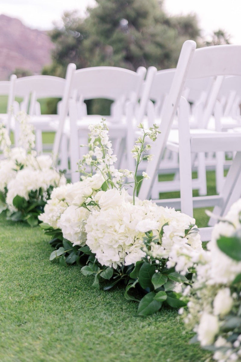 White hydrangea and rose arrangements lining a ceremony aisle