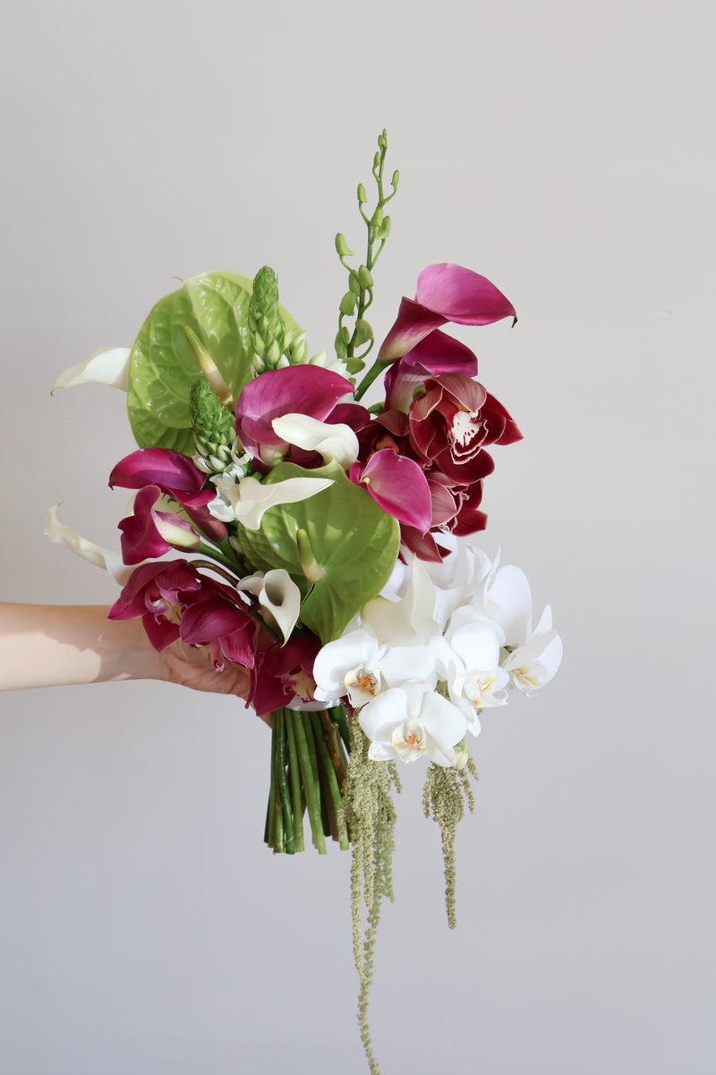 Hand-tied bouquet of green anthurium magenta calla lilies burgundy cymbidium and white phalaenopsis orchids