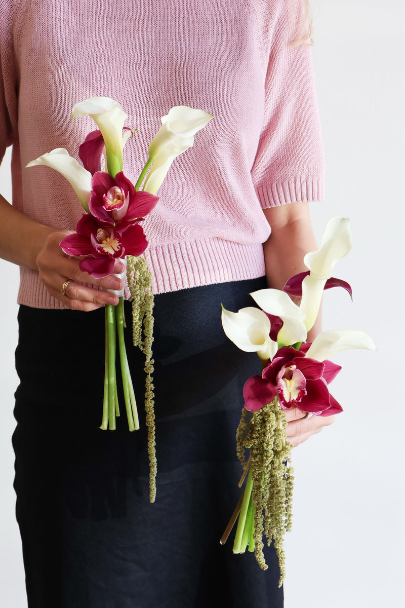 Two small bouquets of white calla lilies burgundy cymbidium orchids and hanging green amaranthus