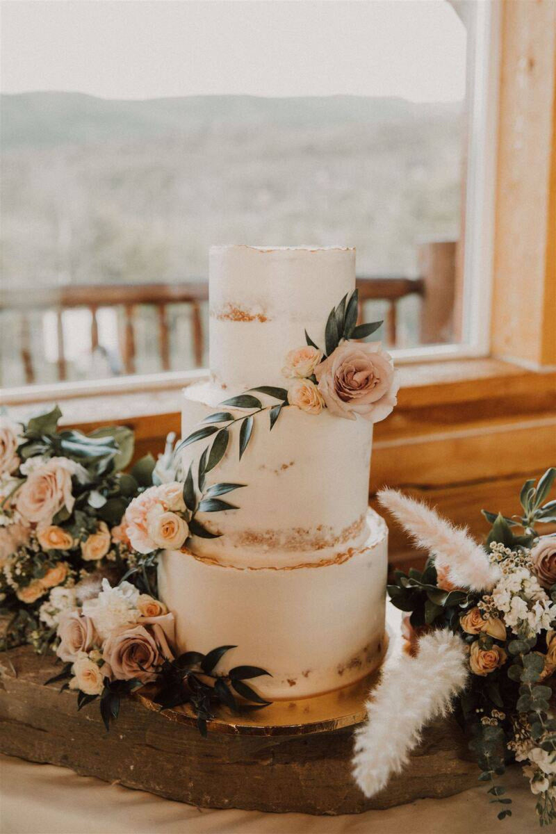 Three-tier semi-naked wedding cake dressed with mauve roses and pampas grass