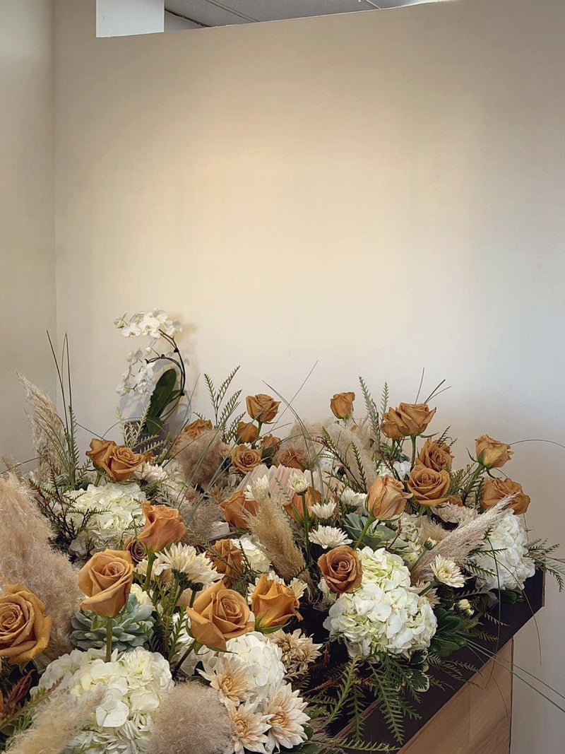 Boho arrangements of toffee roses white hydrangea orchids and pampas