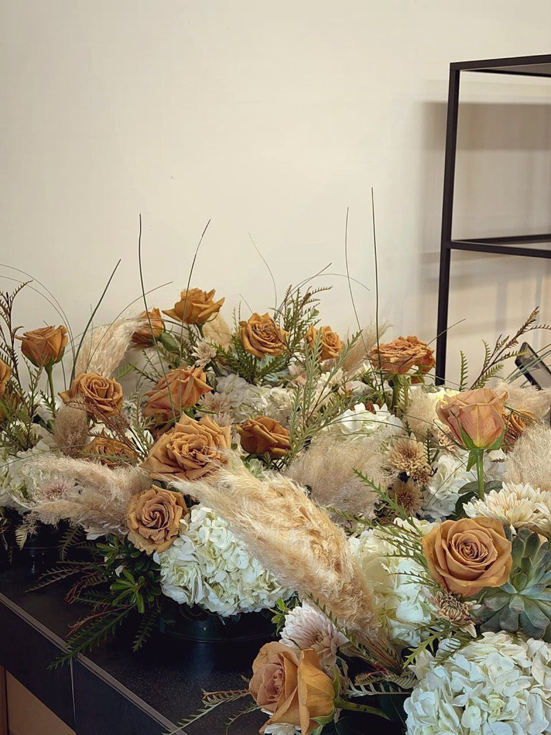 Row of boho centrepieces with toffee roses pampas and succulents