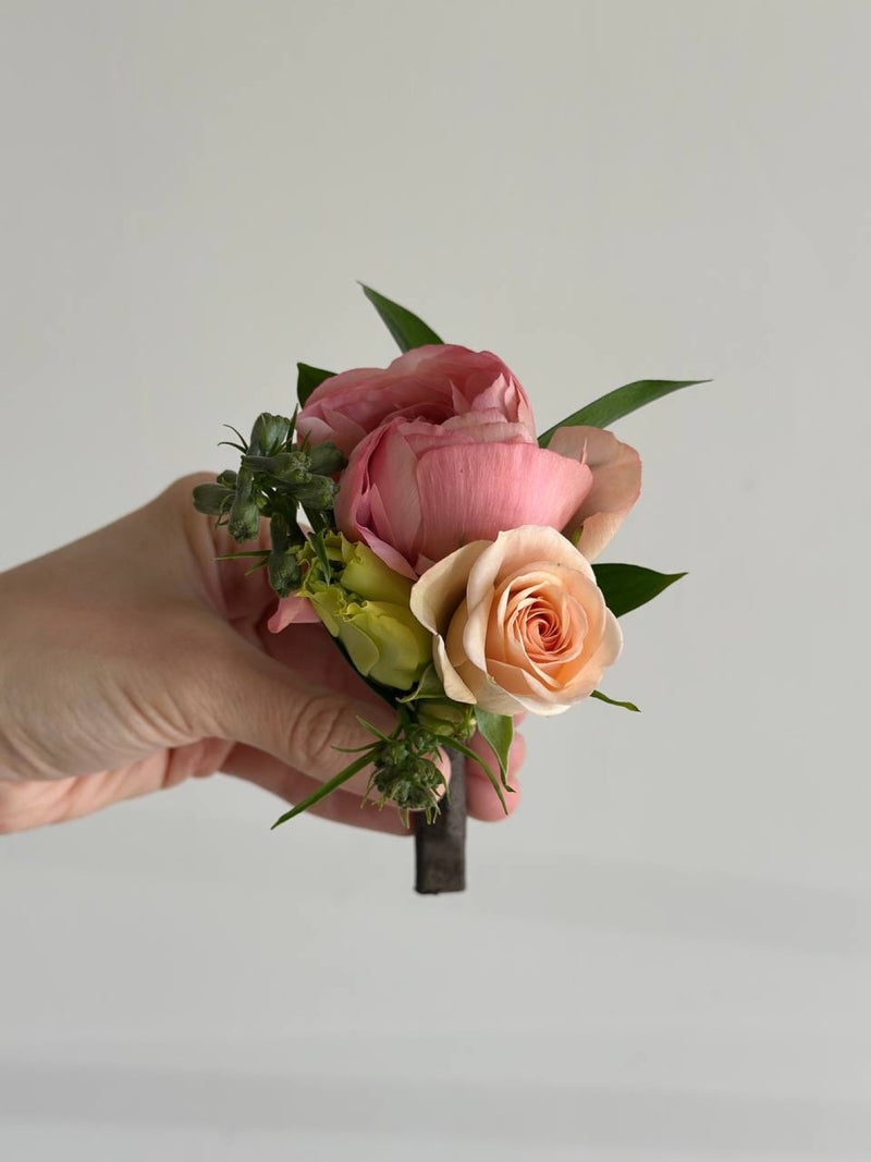 Boutonni&egrave;re of pink and peach garden roses with ruscus