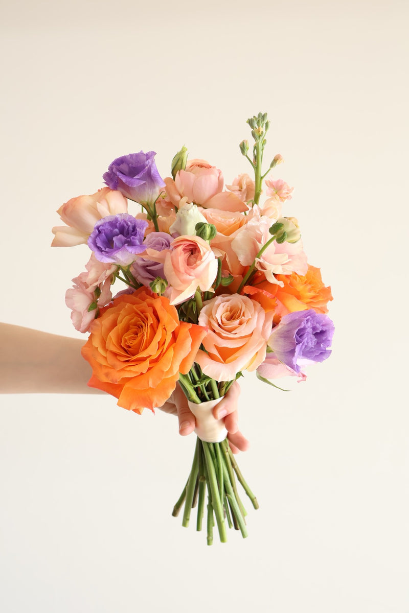 Orange and purple bouquet of roses lisianthus and stock