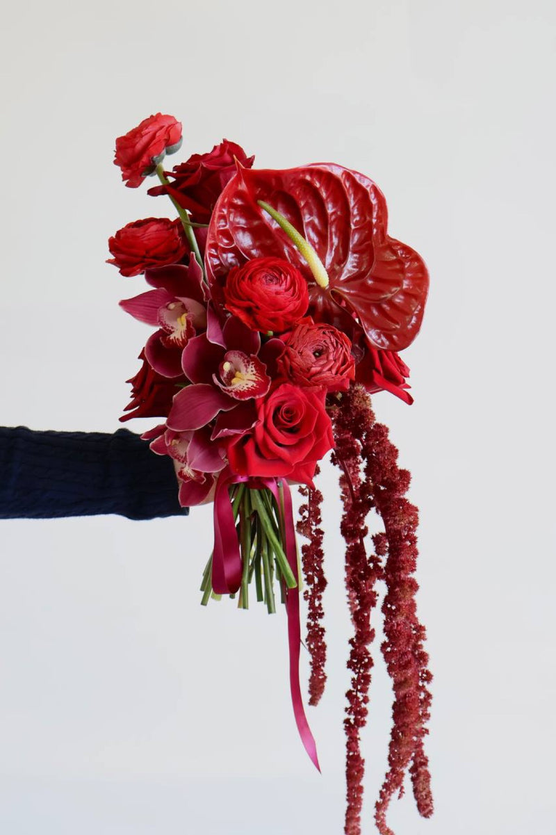 Cascading red bouquet of anthurium cymbidium orchids roses and amaranthus