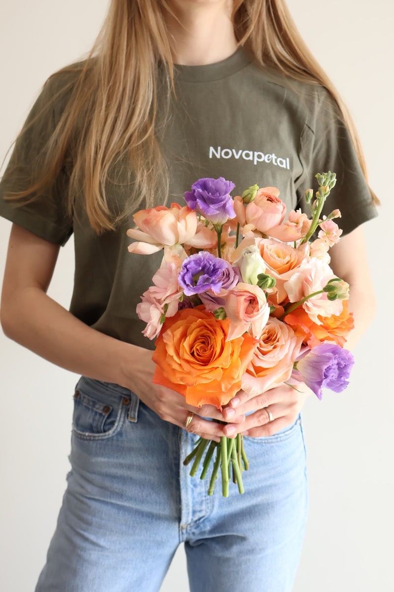 Novapetal florist holding an orange and lilac hand-tied bouquet