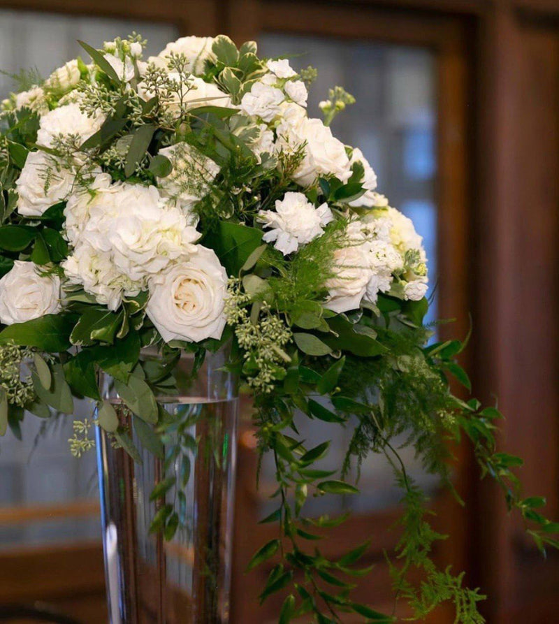 Tall white rose and hydrangea centrepiece on a glass pedestal vase
