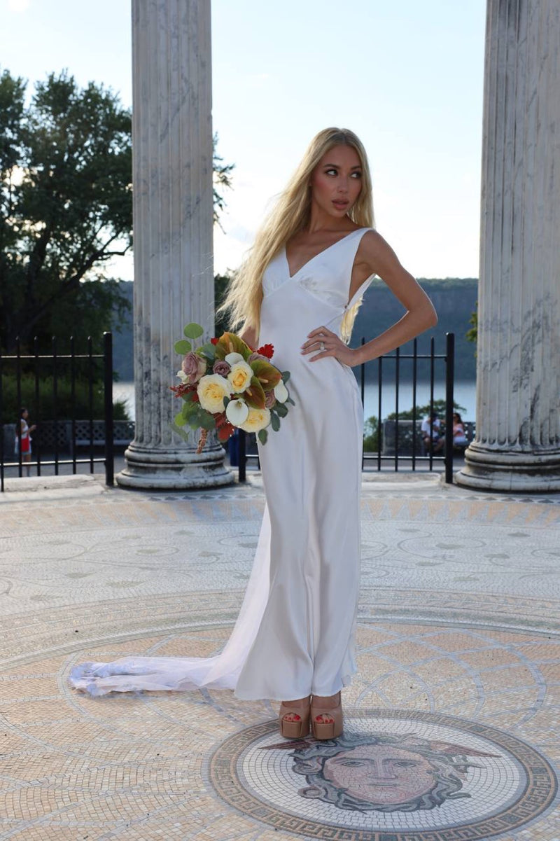 Bride in a column rotunda holding an autumn bouquet of cream roses and oak leaf