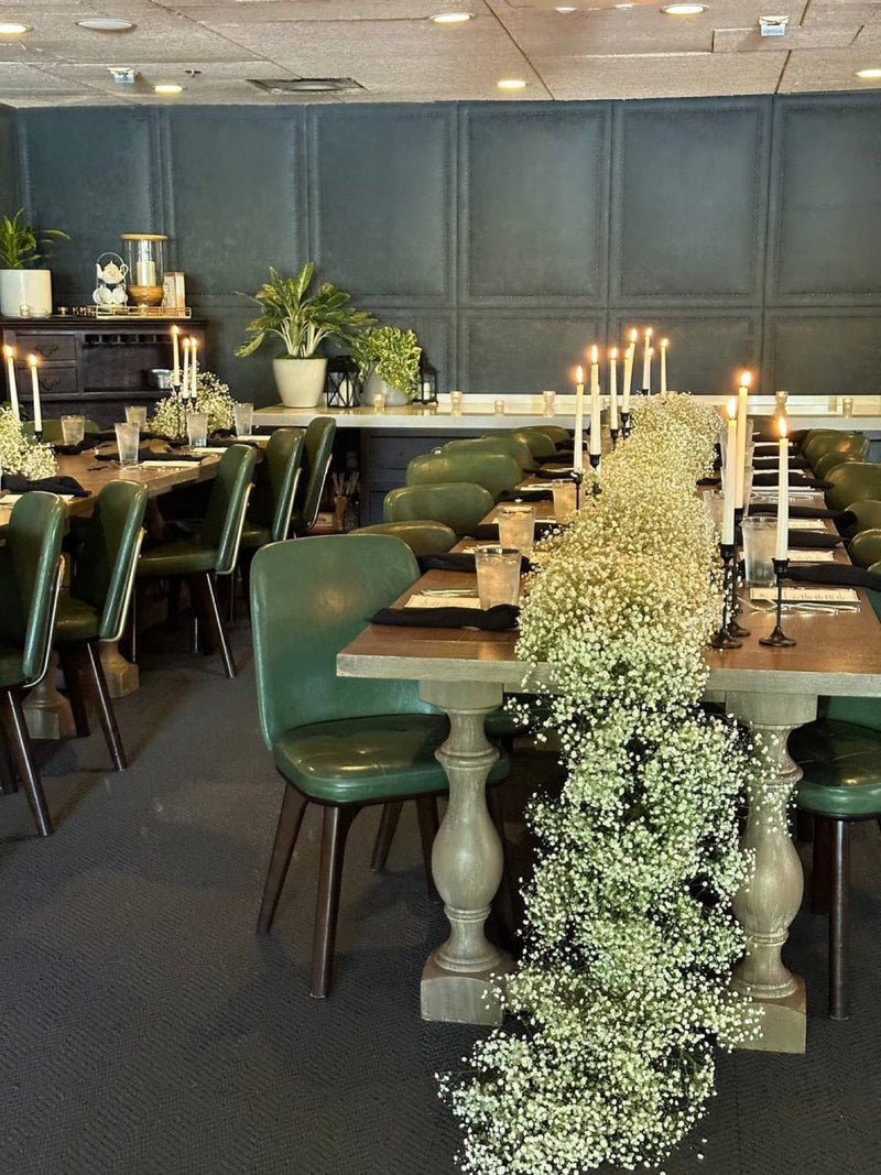 Baby&rsquo;s breath runner cascading down a long table between taper candles