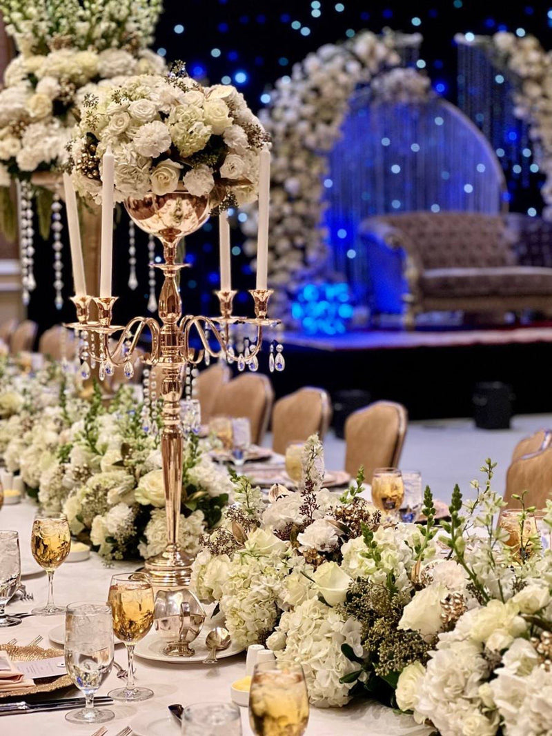 Gold candelabra centrepiece with crystal drops above a white garland