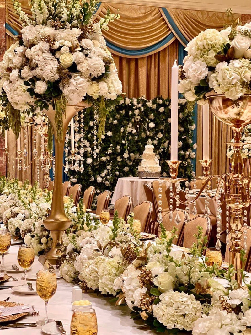 Head table with a flower wall gold candelabra and white garland