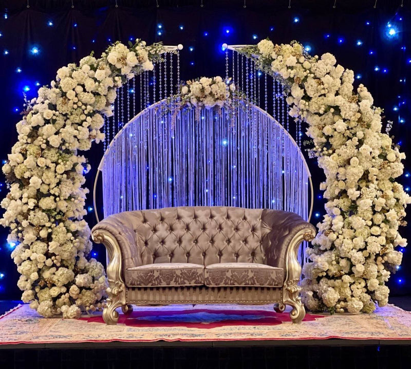 Floral stage arch of white roses and hydrangea against a lit backdrop