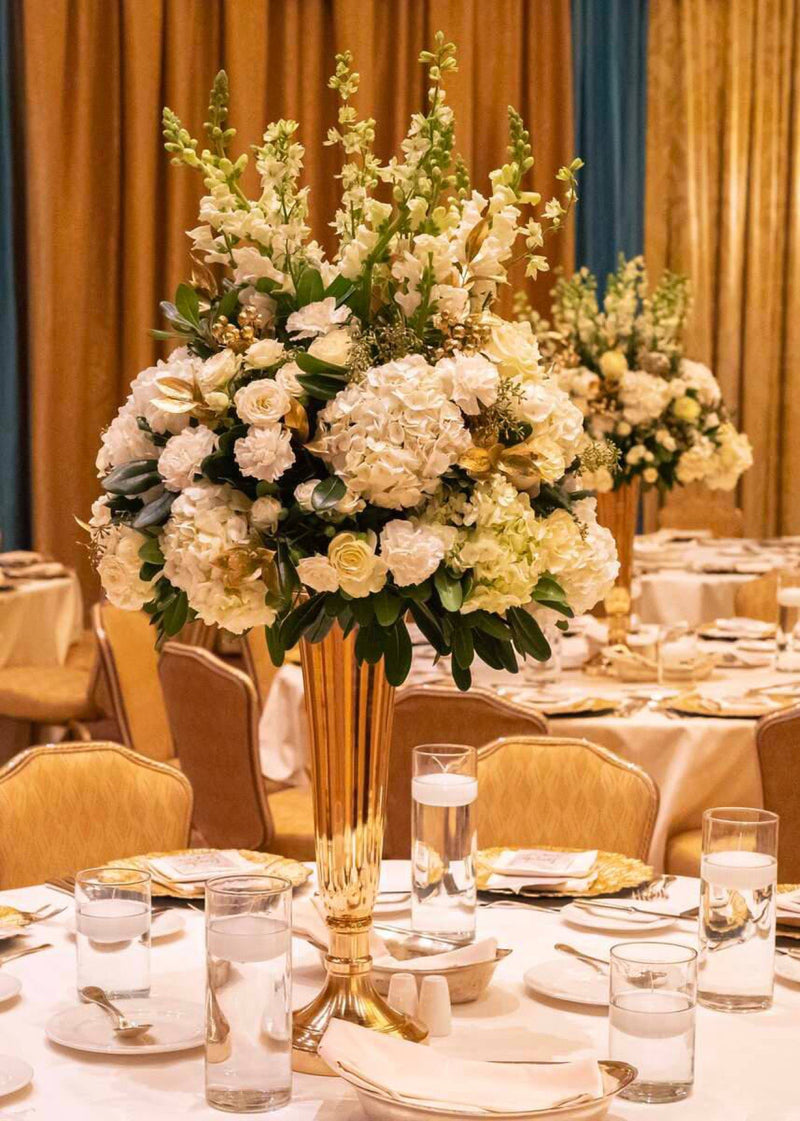 Gold trumpet vase filled with white hydrangea roses and stock