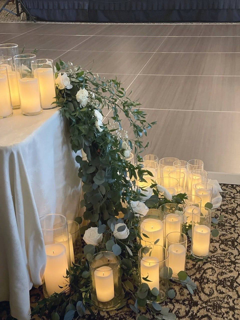 Eucalyptus and white rose garland spilling from a head table into pillar candles