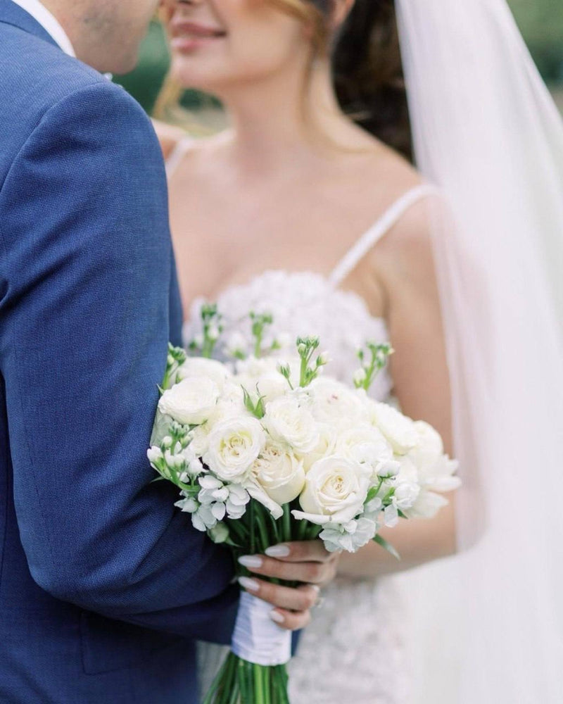 Bride holding a white garden rose and stock bouquet beside the groom