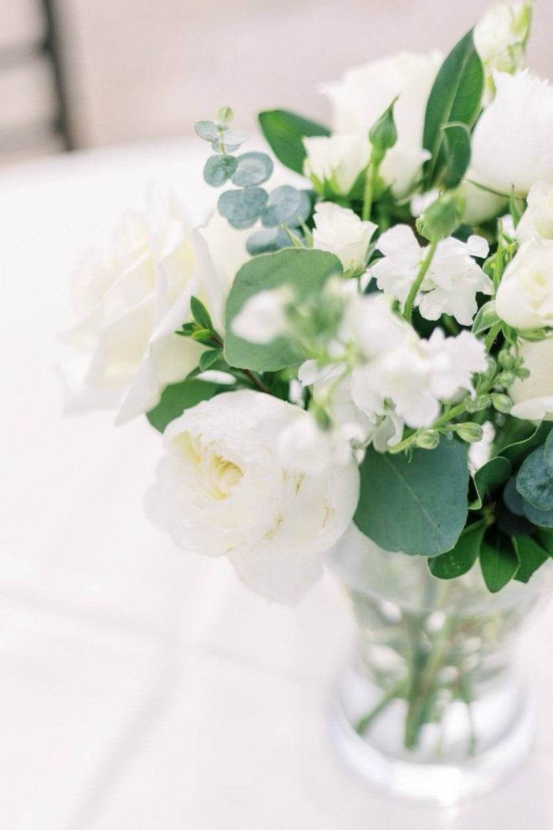White garden roses lisianthus and eucalyptus in a clear glass vase
